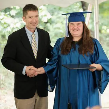 Here's an alt tag for the image: `Proud graduate shakes hands with a man.`