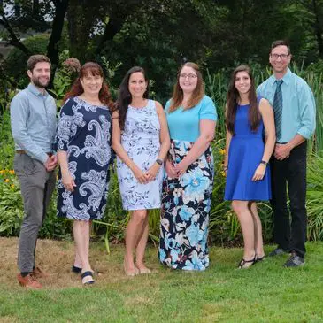 Here's an alt tag for the image: Six people smiling for a group photo.