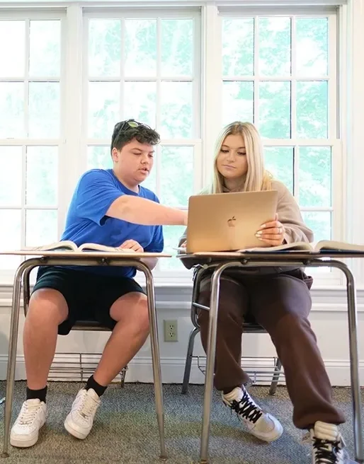 Two students working together on a laptop.