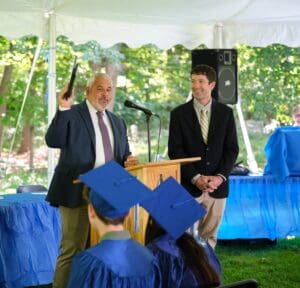 A man giving a speech at an outdoor graduation.