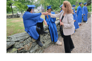 A woman is shaking hands with two graduates.