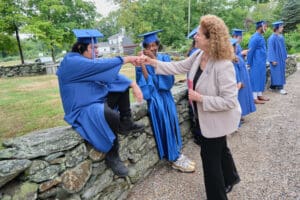 A woman is shaking hands with graduates