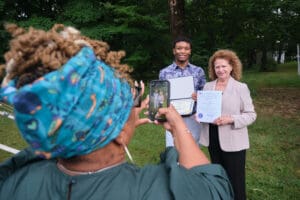 A woman taking a picture of two people holding certificates.