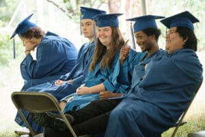 A group of young people sitting in graduation robes.