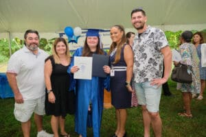 A group of people standing around a woman in graduation gown.