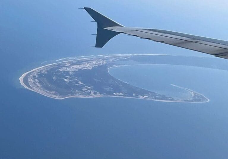 Here's an alt tag for the image: Aerial view of island from airplane wing.