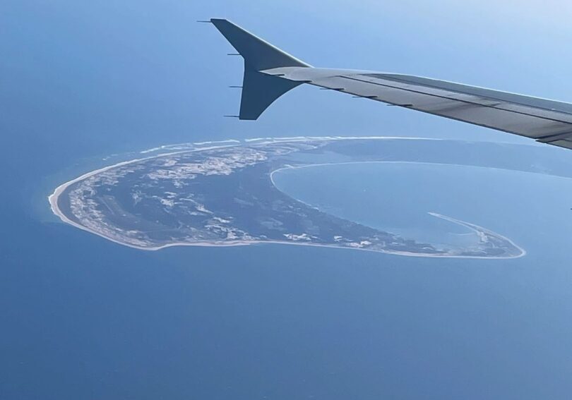 Here's an alt tag for the image: Aerial view of island from airplane wing.