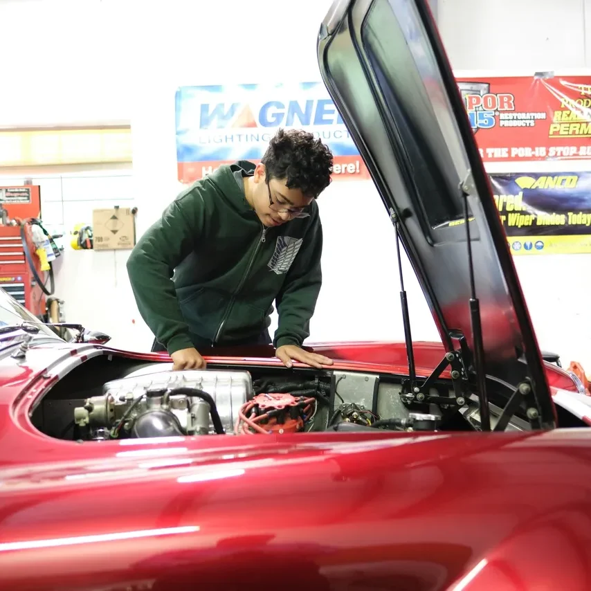 Mechanic inspecting red classic car engine.