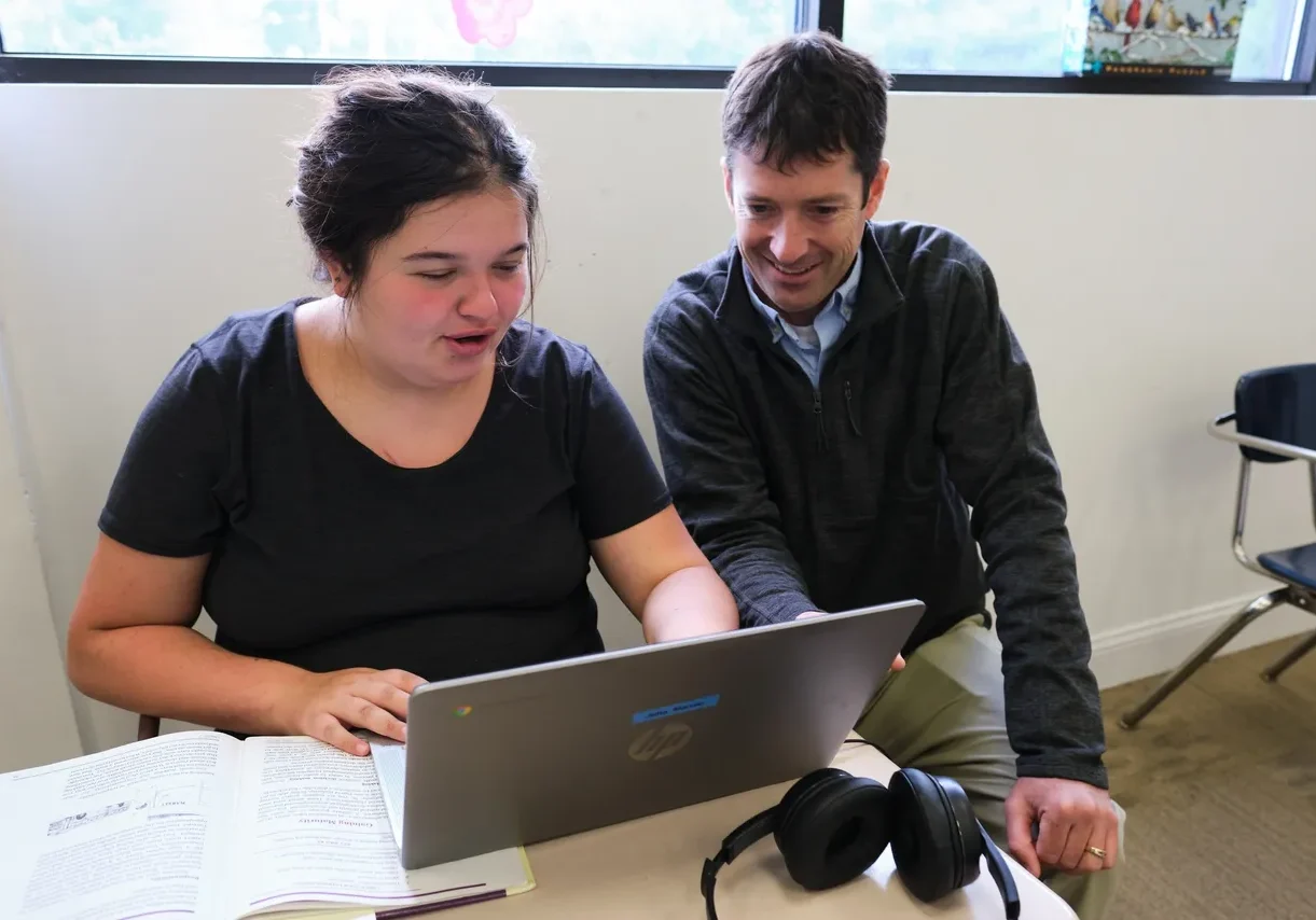 Teacher and student using laptop together.